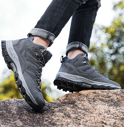 Ein Mann trägt die Grauen Expedition Outdoor Barfußschuhe von Vanea bei einer Wanderung in den Bergen